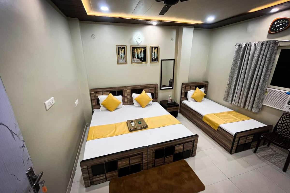 A hotel room with two beds, a ceiling fan, a clock, and a window with curtains.