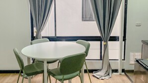 A room with a round table and four chairs, large windows with grey curtains, and a white ceiling. - Centrally located apartment near airport, terminal, US Embassy (Bogotá)