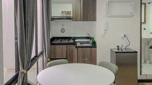 A modern kitchen with a round dining table and four chairs, a refrigerator, and a sink. - Centrally located apartment near airport, terminal, US Embassy (Bogotá)