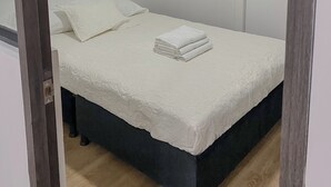 A small, neatly made bed with a white duvet and folded towels, a dark-colored headboard, and a simple, clean room design. - Centrally located apartment near airport, terminal, US Embassy (Bogotá)