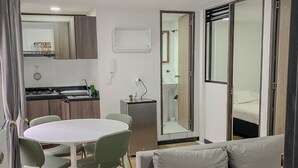 A modern living room with a grey sofa, a round dining table with chairs, and a kitchen area with a stove and cabinets. - Centrally located apartment near airport, terminal, US Embassy (Bogotá)