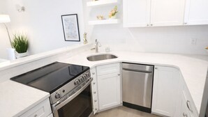 A modern kitchen with white cabinetry, a black stove, a dishwasher, and a sink. - Spectacular Ocean Front Condo Downtown Rehoboth Beach, Delaware! (Rehoboth Beach)
