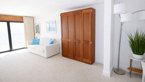 A modern living room with a white sofa, a large wooden wardrobe, and a floor lamp. - Spectacular Ocean Front Condo Downtown Rehoboth Beach, Delaware! (Rehoboth Beach)