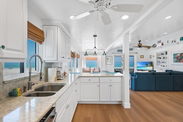 A modern kitchen with white cabinets, a marble countertop, and a built-in island. - 3106 Ave F - The Retreat 3 Bedroom Home (Holmes Beach)