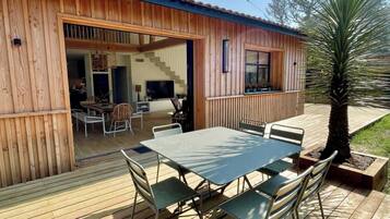 Une maison en bois avec une terrasse, une table à manger et des chaises.