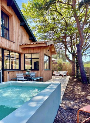 Ein Holzhaus mit Pool, Sitzgelegenheit im Freien und einem großen Baum.