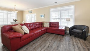 Un soggiorno con un divano a quattro posti in pelle rossa, una poltrona nera e un pavimento in legno.