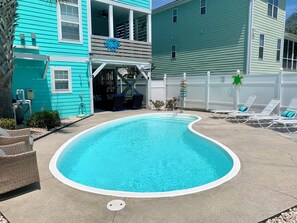 A swimming pool with a white edge, surrounded by lounge chairs and a covered area with a ceiling fan. - 5 BR,  Walk To The Beach, Private Pool - A Son Of A Sailor (Surfside Beach)