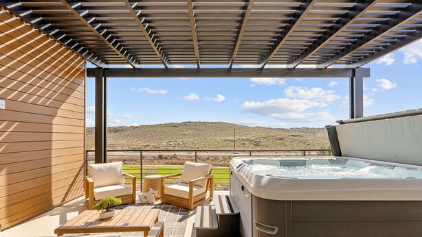 Eine Dachterrasse mit Whirlpool, Holzmöbeln und Blick auf eine hügelige Landschaft.