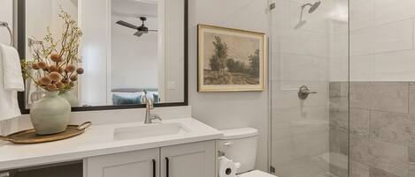 Une salle de bain moderne avec un lavabo blanc, des toilettes et une douche à parois de verre.