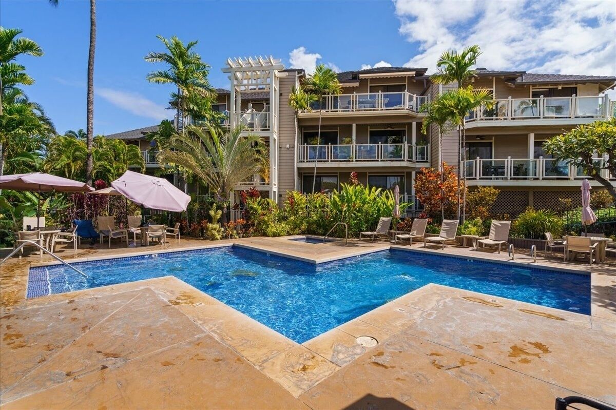 A hotel with a swimming pool, multiple balconies, and lush landscaping.