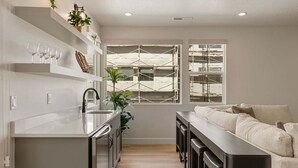 A modern kitchen with a central island, built-in shelves, and a large window with scaffolding. - Rockaction Destination 5 Bedroom Townhouse (St. George)