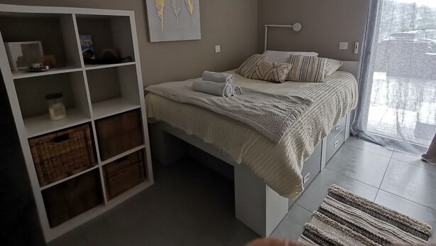 Et soveværelse med en seng, et hvidt skab, et vindue med udsigt og en loftlampe.