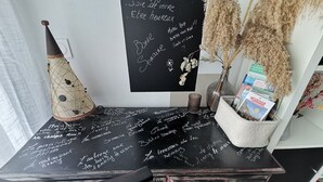 Tavle med håndskrevne noter, en dekorativ kegle og en vase med tørrede planter.