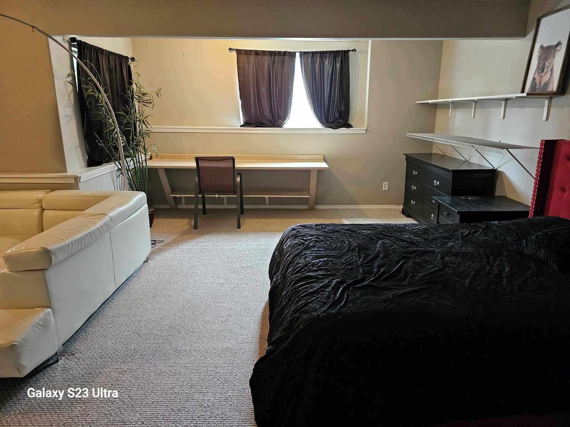 Un dormitorio con cama, escritorio, silla, cómoda y ventana con cortinas.