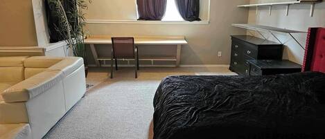 Un dormitorio con cama, escritorio, silla, cómoda y ventana con cortinas.