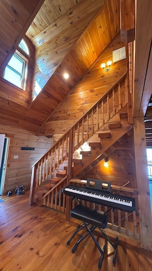 Un intérieur en bois avec un escalier, un piano et une fenêtre.