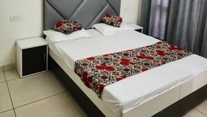 A bedroom with a bed, a nightstand, an air conditioner, and a curtain. - Rathi Residency I Ambala (Ambala)