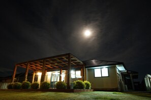 Una casa con porche cubierto, una ventana a la vista y la luna en el cielo.
