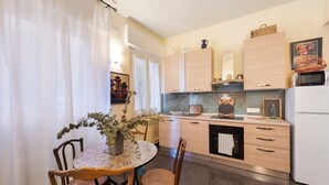 Una cocina compacta con muebles de madera, una mesa de comedor con sillas y un refrigerador.