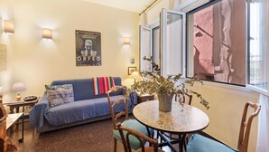 Una sala de estar acogedora con un sofá, una mesa de comedor y un ventanal grande.
