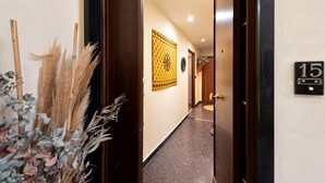 A hallway with a door labeled '15', a patterned wall hanging, and a plant with pampas grass and eucalyptus leaves. - Apartment 'Casa Luna' Opposite Genoa Aquarium (Genova)
