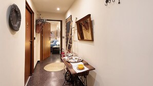 A hallway with a wooden door, a wall-mounted mirror, a wall-mounted hook system, and a table with a basket and a plate. - Apartment 'Casa Luna' Opposite Genoa Aquarium (Genova)