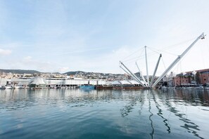 A waterfront view with a distinctive white cable-stayed bridge, calm water, and a cityscape in the background. - Apartment 'Casa Luna' Opposite Genoa Aquarium (Genova)