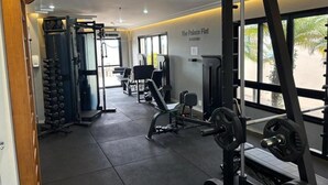 A gym with weightlifting equipment, benches, and a wall sign reading 'The Palace Flat.' - The Palace Moema 501 (São Paulo)