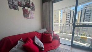 A bedroom with a large bed, a view of buildings through a balcony, and several wall-mounted pictures. - The Palace Moema 501 (São Paulo)