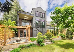 Ein modernes, zweistöckiges Haus mit Balkon, Feuerstelle und gepflegtem Garten.