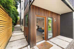 Une maison moderne avec une façade en bois, une cuisine ouverte et un salon comprenant un canapé et une table basse.