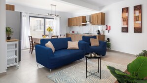 A modern living room with a blue sofa, a small side table, and a patterned rug. - Chic Stay Near Yacht Marina 2 Balconies (Pietà)