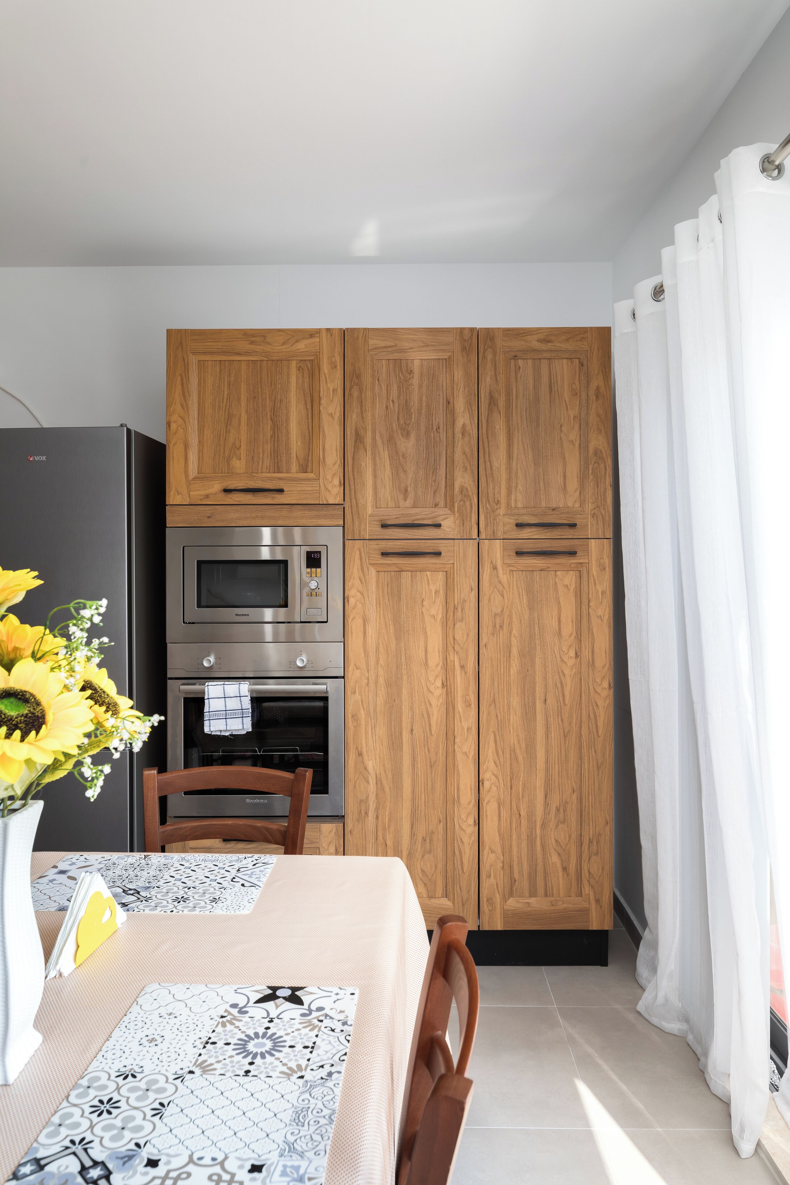 Een moderne keuken met houten kastjes, een inbouwoven en een magnetron.