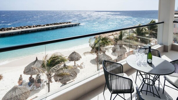 Ein Balkon mit Meerblick, ein Pool und Strandstühle.