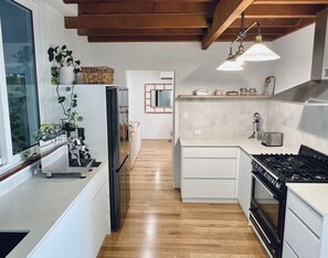 A modern kitchen with wooden beams, a refrigerator, a stove, and a sink.