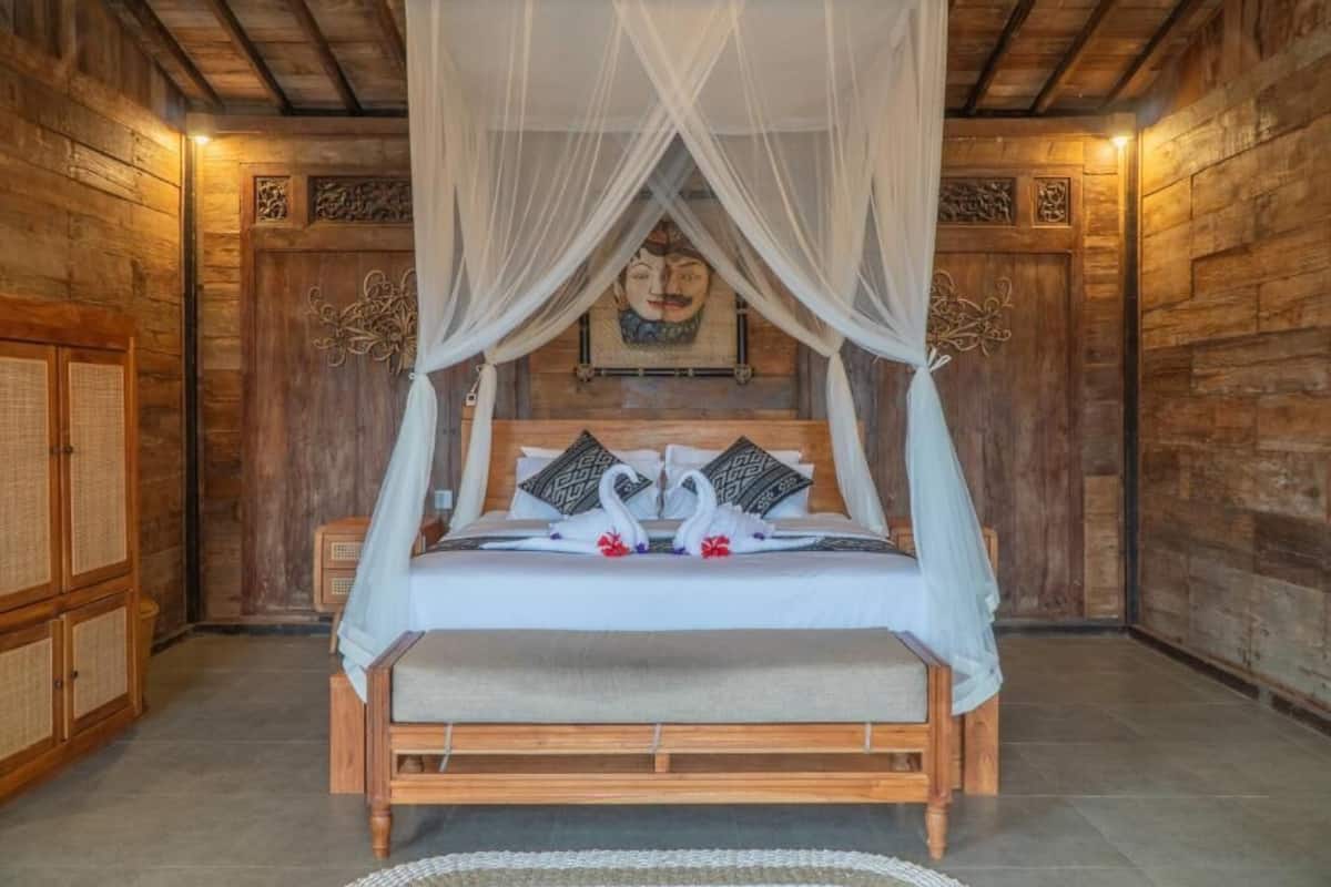 A wooden four-poster bed with a canopy, white bedding, and decorative pillows.