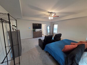 A bedroom with a bed, a ceiling fan, a dresser, a TV, and a window. - Luxurious 5-bedroom home in beautiful Graniteville, SC (Graniteville)