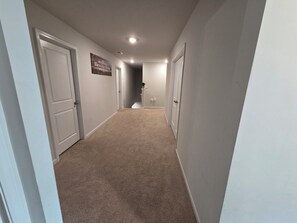 A hallway with carpeted floors, white walls, and closed doors. - Luxurious 5-bedroom home in beautiful Graniteville, SC (Graniteville)