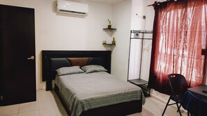 A bedroom with a bed, a desk, a chair, a wardrobe, and a potted plant.