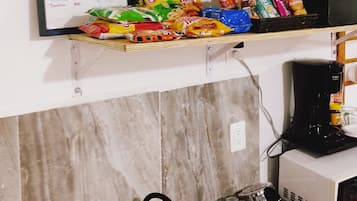 A kitchen with a sink, a coffee maker, and a snack bar sign listing prices.