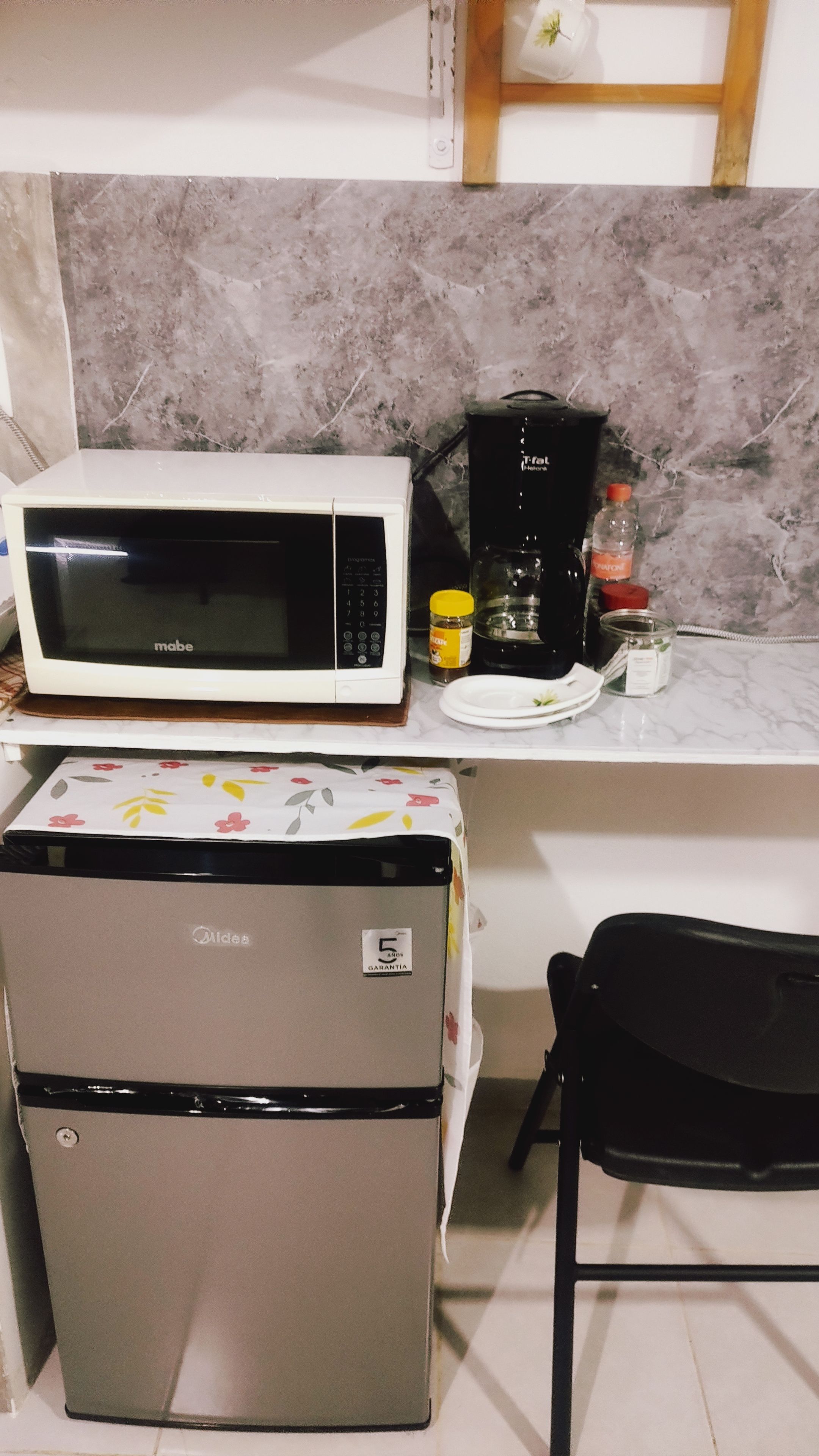 A compact kitchen with a microwave, coffee maker, refrigerator, and a small dining table.