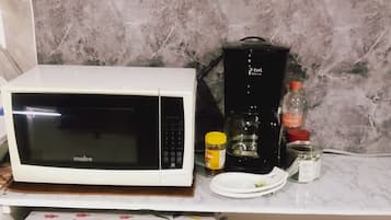 A compact kitchen with a microwave, coffee maker, refrigerator, and a small dining table.
