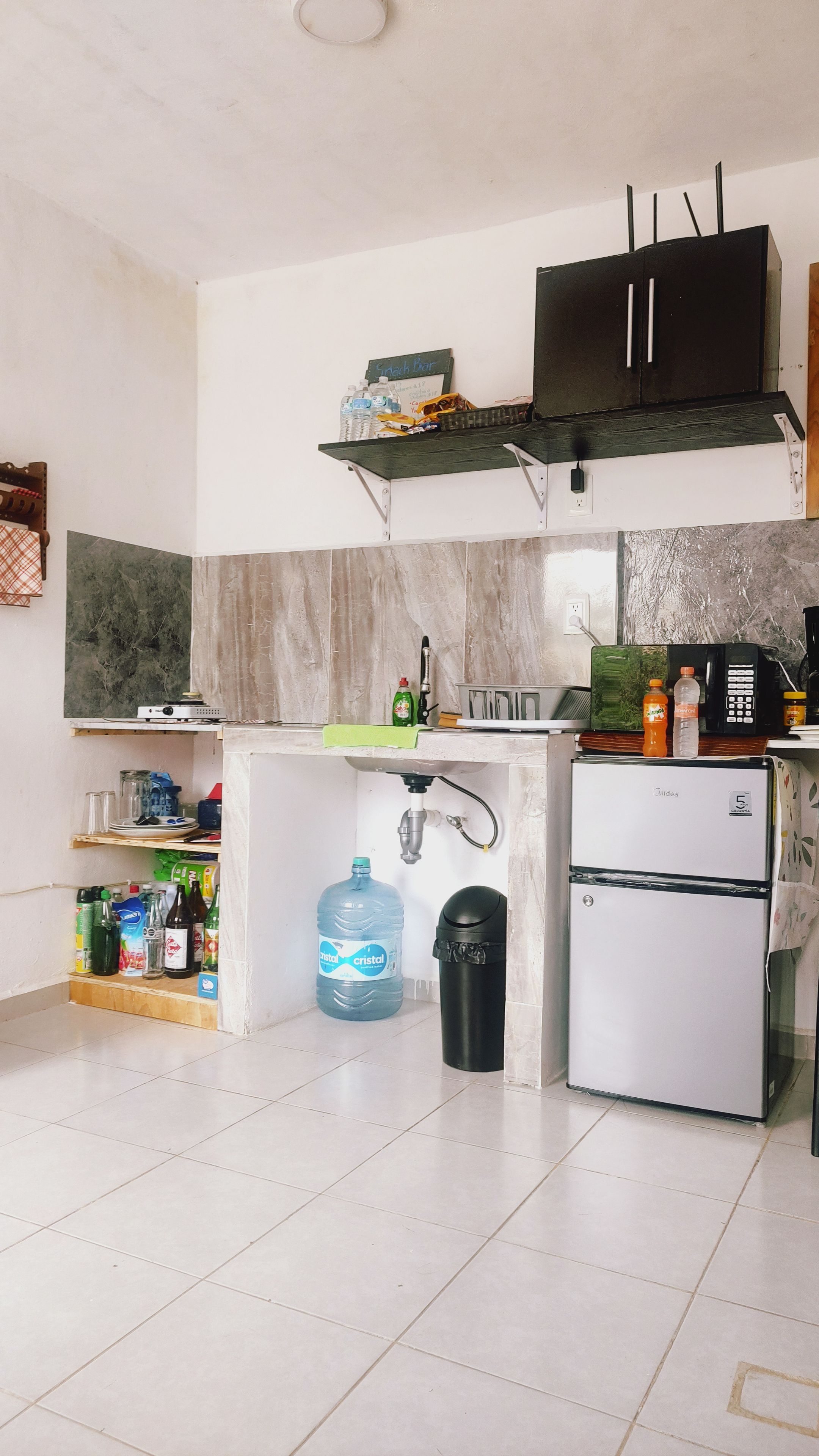 Un angolo cottura funzionale con frigorifero, microonde e dispenser di acqua.