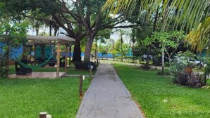 A pathway leading through a garden with a gazebo, trees, and a hammock. - Pousada Bom Jardim (Nobres)