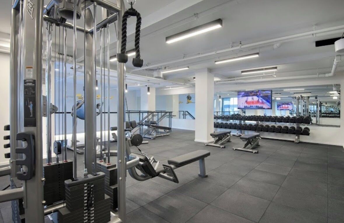 Ein Fitnessraum mit Gewährleistungsausrüstung, Bänken und Kurzhanteln.