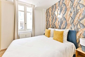 Ein Schlafzimmer mit einem großen Bett, einem Fenster und einer Wand mit Blätermotiv.