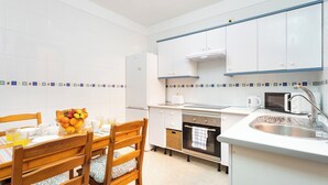 Een moderne keuken met witte kasten, een roestvrijstalen spoelbak en een eethoek met houten stoelen en een ontbijt gedekte tafel.