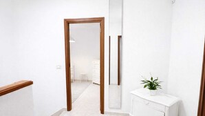 Een hal met een houten deur, een witte dressoir en een spiegel.