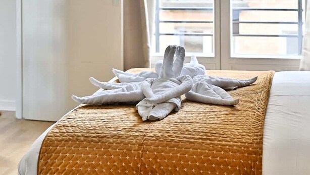 Ett hotellrum med en säng, ett fönster och utsikt över byggnaderna utanför.